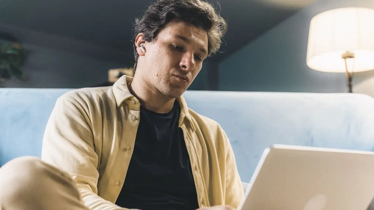 Joven estudiando en la noche con su laptop bajo una luz cálida después del trabajo