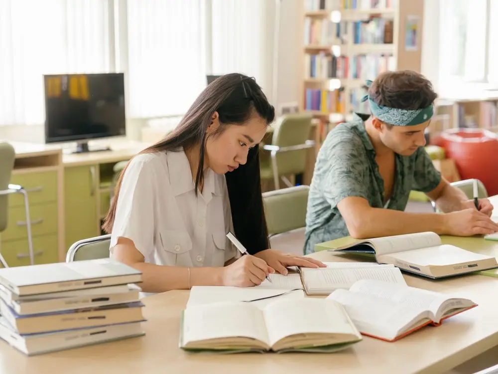 Estudiantes estudiando y tomando notas en la biblioteca