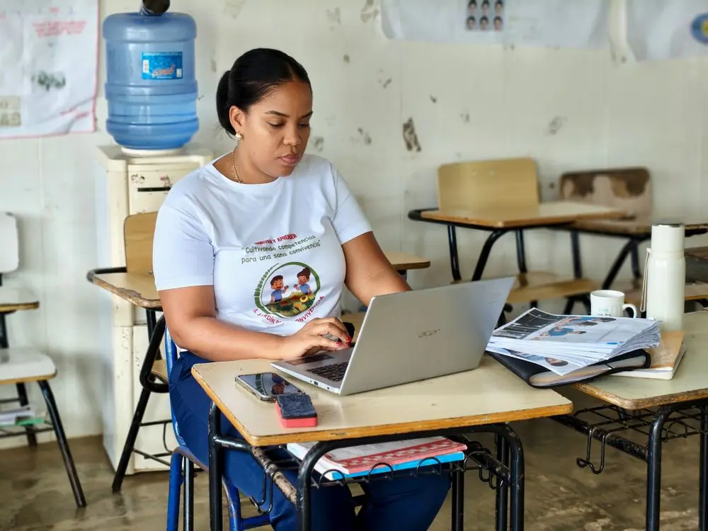 Estudiante trabajando en una computadora dentro de un aula